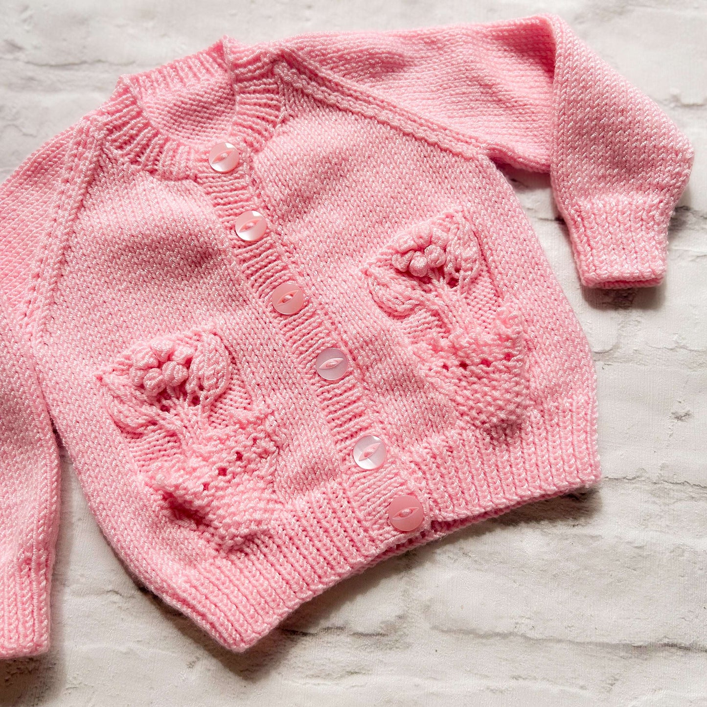 Hand knitted personalised baby cardigan in pink with flower pocket detail size 3-6 months — made to order in the UK | Little Name Knits