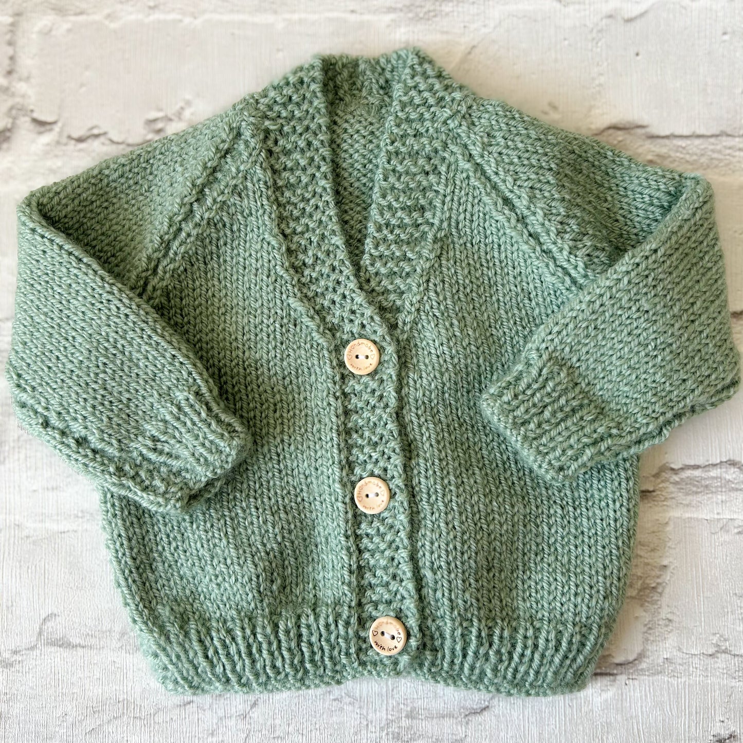 Hand knitted personalised baby cardigan in sage size 0-3 months — made to order in the UK | Little Name Knits